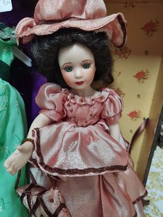 a close up of a doll in a dress and hat