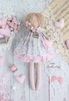 a doll is laying on the floor next to some pink hearts and lace doily