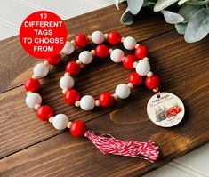 a red, white and blue beaded necklace on a wooden table next to a potted plant