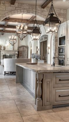 a large kitchen with an island and chandelier hanging from it's ceiling