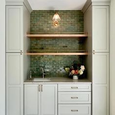 a kitchen with white cabinets and green brick backsplashing on the back wall