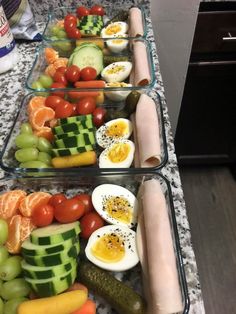 two plastic trays filled with different types of vegetables and eggs on top of a counter