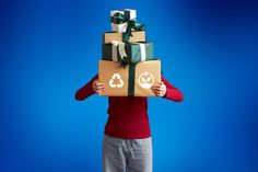 a woman holding a stack of boxes with recyclables on top of it