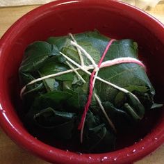 a red bowl filled with green leafy vegetables