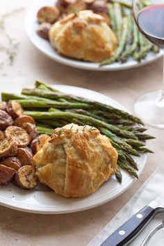 asparagus, potatoes and sausage on a white plate with red wine in the background