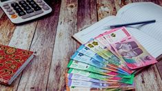 a pile of money sitting on top of a wooden table next to a calculator