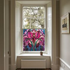 a stained glass window in the corner of a room with wood flooring and white walls