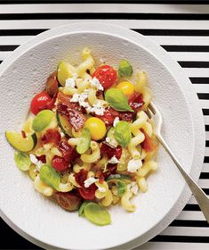 a white bowl filled with pasta and vegetables on top of a black and white table cloth