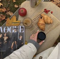 a person sitting at a table with an apple, coffee and croissant on it