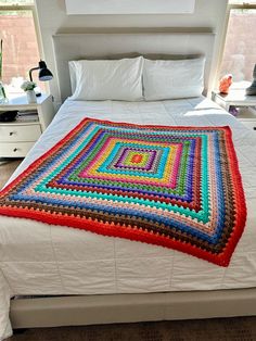 a crocheted blanket on top of a bed in a room with white walls