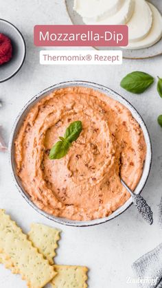 a bowl filled with hummus next to crackers