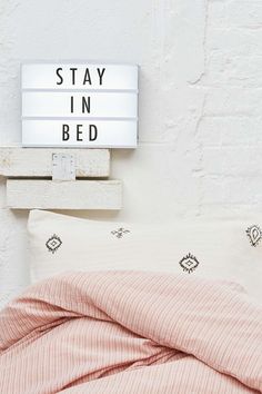 a bed with a light up sign on the wall above it that says stay in bed