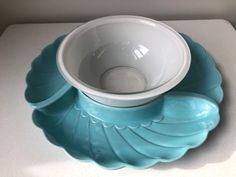 a bowl and saucer sitting on top of a blue plate with scalloped edges