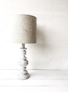 a white lamp sitting on top of a wooden table next to a light brown shade