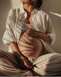 a pregnant woman sitting on the floor with her stomach exposed