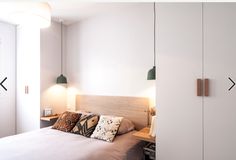 a bed sitting in a bedroom next to a wall mounted light on it's side