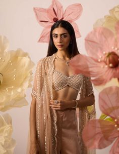 Embrace ethereal elegance in this peach cape set, adorned with intricate hand embroidery. The cape & blouse feature pearl embroidery and is based on net fabric. The pants are beautifully curated on modal satin. The delicate cascade of the cape complements the allure of the bustier and pant ensemble, creating a harmonious symphony of sophistication. Step into luxury, where every stitch tells a tale of timeless beauty. Cape Blouse, Cape Set, Ethereal Elegance, Pearl Embroidery, Net Fabric, Timeless Treasures, Pant Set, Timeless Beauty, Hand Embroidery