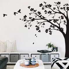 a living room with a tree and birds painted on it's wall in black