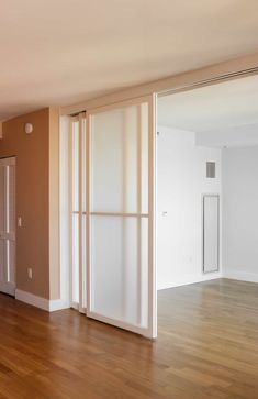 an empty room with sliding doors and hard wood flooring