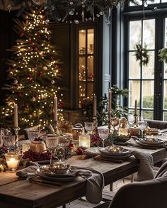 a dining room table set for christmas dinner with candles, plates and glasses on it