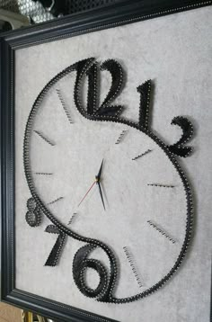 a clock made out of black beads is hanging on the wall