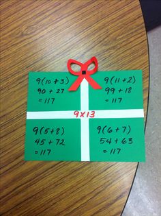 a piece of paper with a red bow on it sitting on top of a wooden table