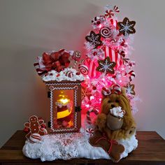 a teddy bear sitting in front of a christmas tree decorated with gingerbreads and candy canes