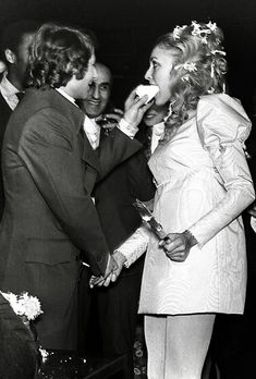 black and white photograph of two people feeding each other cake at a wedding reception in the 1950's