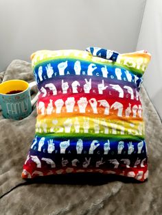 two pillows and a cup on a bed with a pillow cover that has elephants on it