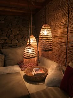 two lamps hanging over a couch in a room with pillows and pillows on the floor