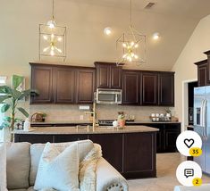 a living room and kitchen area in a house with dark wood cabinets, stainless steel appliances, and white couches