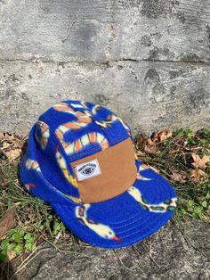 "This 5-panel hat is made from polar fleece with a super fun all-over snake print on a royal blue background. A combination of our traditional 5-panel camp hat style blended with the warmth of our Backcountry Hat's fold-over earflap panel. The front panel is a caramel-colored canvas with a woven Ministry of Culture logo in the upper corner. Fuzzy fleece ear flaps keep you warm when out and about during the winter months and can be folded up when not in use. The hat has an adjustable nylon pull t Culture Logo, Camp Hat, Royal Blue Background, Fleece Hats, Canvas Hat, Blue Snake, 5 Panel Hat, Five Panel, Hat Style