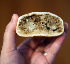 a person holding up a piece of bread with meat and cheese on it in their hand