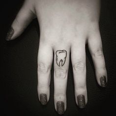 a person's hand with a small tooth tattoo on the middle finger and an outline of a tooth