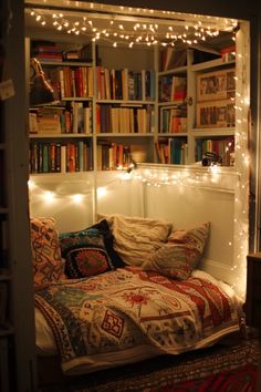 a bed in a room with bookshelves full of books and lights on the wall