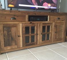 a flat screen tv sitting on top of a wooden entertainment center in a living room