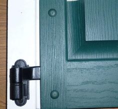 a close up of a door handle on a wooden door with green paint and white trim