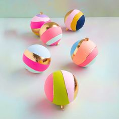 four different colored balls are arranged in a circle on a table, one is gold and the other is pink