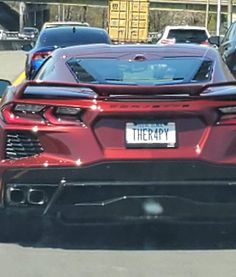 the rear end of a red sports car parked in a parking lot with other cars