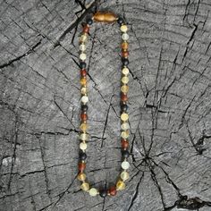 a beaded necklace is sitting on top of a piece of tree bark with beads