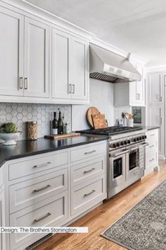 a kitchen with white cabinets and black counter tops is pictured in this image, there is a rug on the floor next to the stove