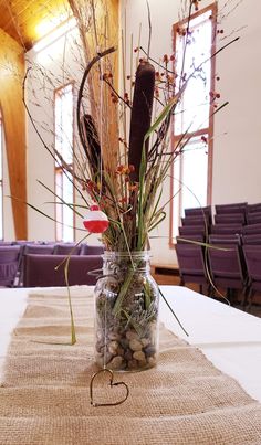 a vase filled with plants and rocks on top of a table in front of purple chairs