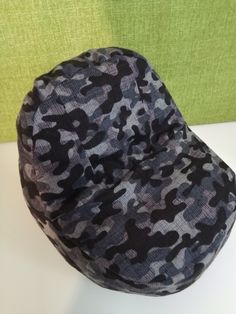 a black and gray camouflage print bean bag sitting on top of a white table next to a green wall