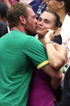 a man and woman embracing each other in front of a crowd