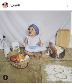 a baby sitting on the floor next to some bread