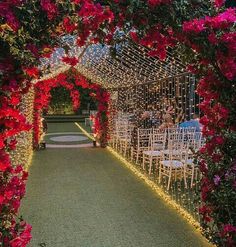 an outdoor wedding venue with red flowers on the aisle and white chairs in the middle