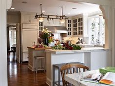 an open book is sitting on a table in the middle of a kitchen with white cabinets