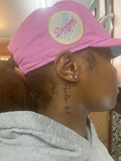 a woman with a tattoo on her neck wearing a pink hat and ear piercings