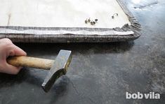 a person holding a hammer in front of a piece of fabric with studs on it