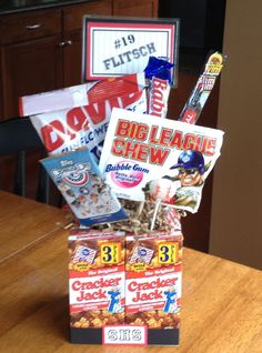 a box filled with snacks sitting on top of a wooden table next to a sign that says big league chew